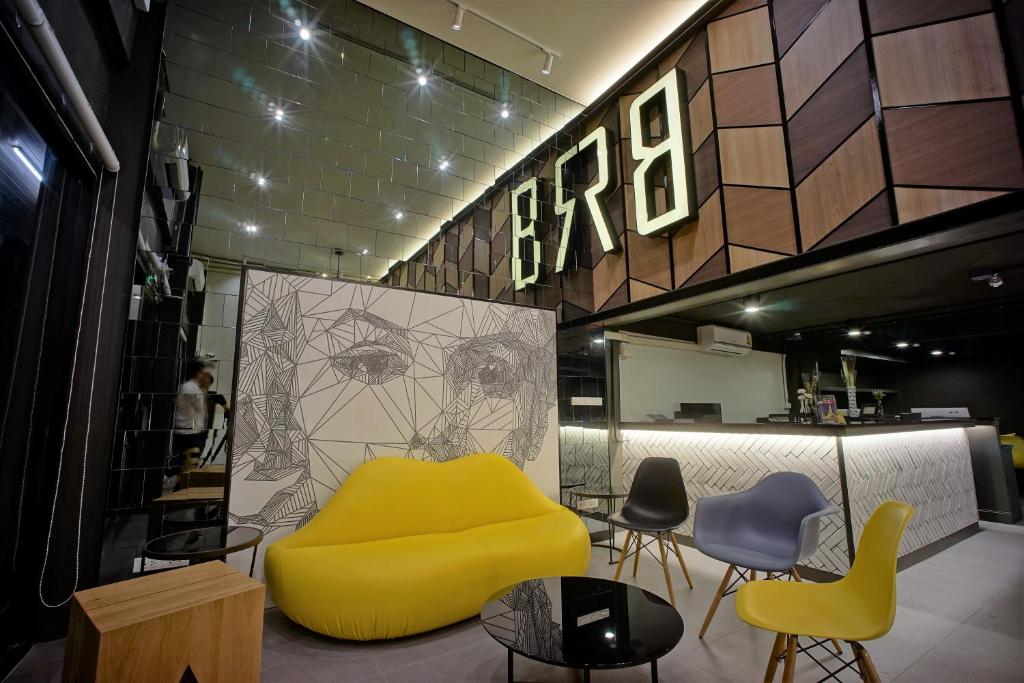 a yellow couch in a room with chairs and tables at BRB Hostel Bangkok Silom in Bangkok