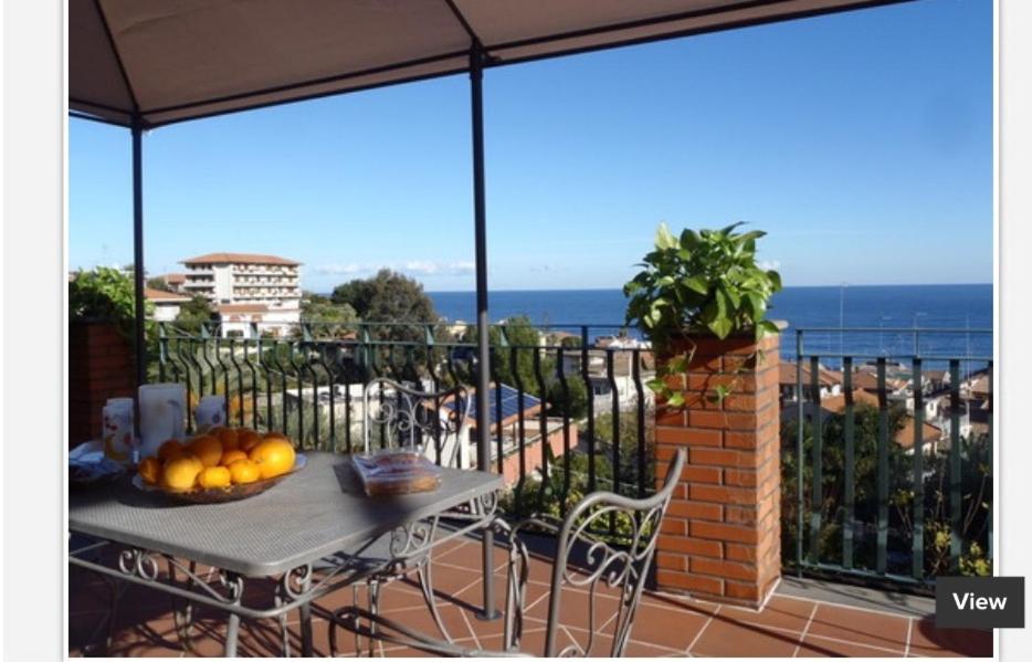 a table on a balcony with a view of the ocean at La Magnolia in Acitrezza