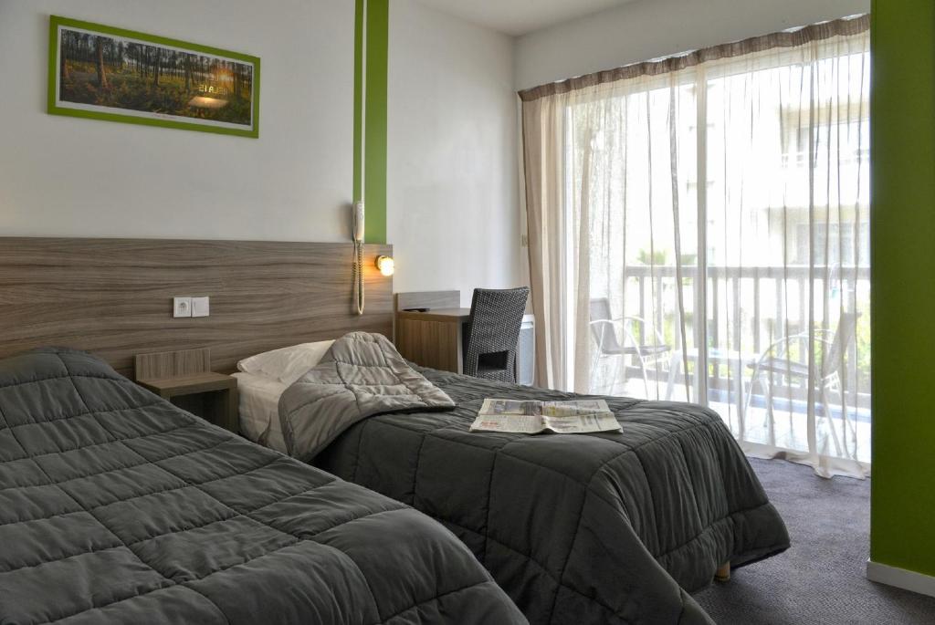 um quarto de hotel com duas camas e uma janela em Hôtel Le Relais Dax em Dax
