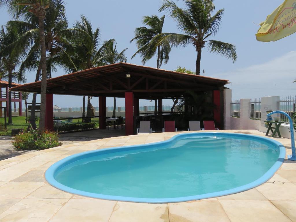 a large swimming pool with a gazebo at Red House Pousada in Flecheiras