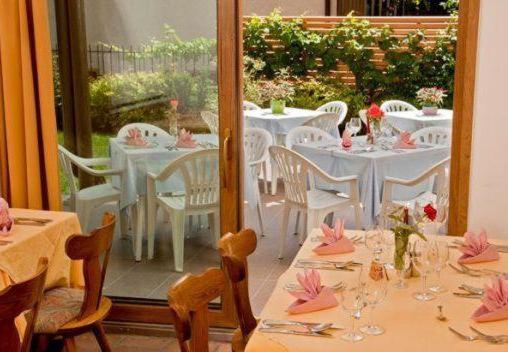 una sala da pranzo con tavoli bianchi e sedie bianche di Pension Steingarten ad Appiano sulla Strada del Vino