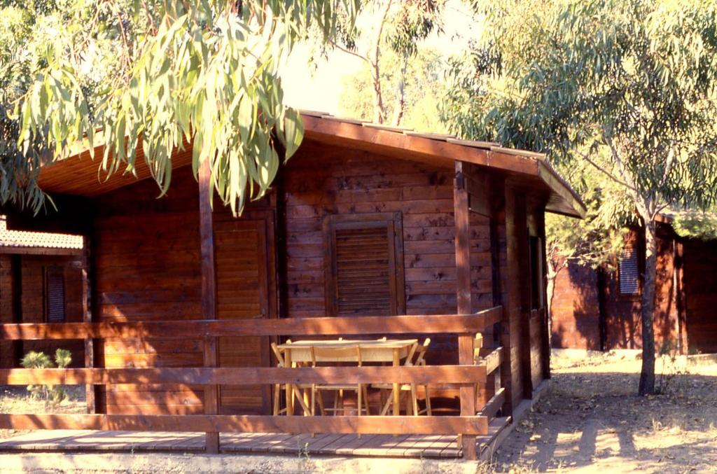 una baita di tronchi con una panchina di fronte ad essa di Villaggio Camping Uria a Foce Varano