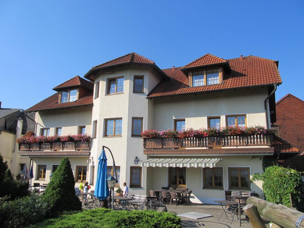 a large white building with a balcony and tables at Pension und Bauernhof Petzold in Greiz
