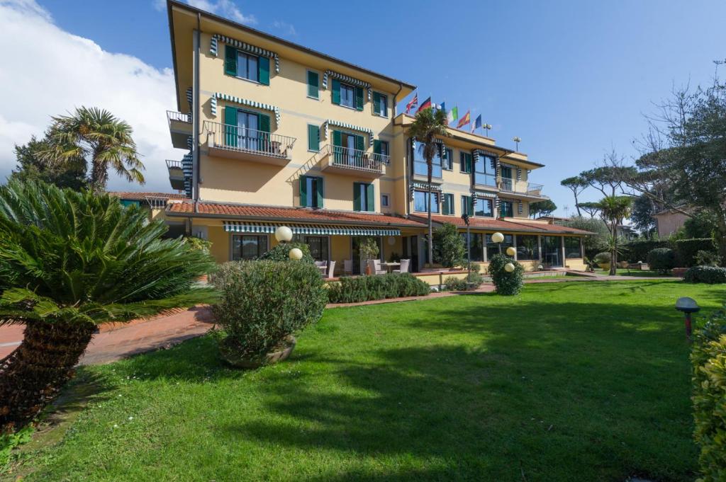 a large building with a lawn in front of it at Hotel Gemma Del Mare in Marina di Pietrasanta