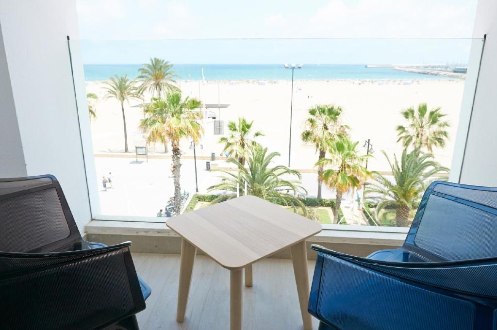 バレンシアにあるHotel Sabbia by Gabbeachのビーチを望む客室で、テーブルと椅子が備わります。
