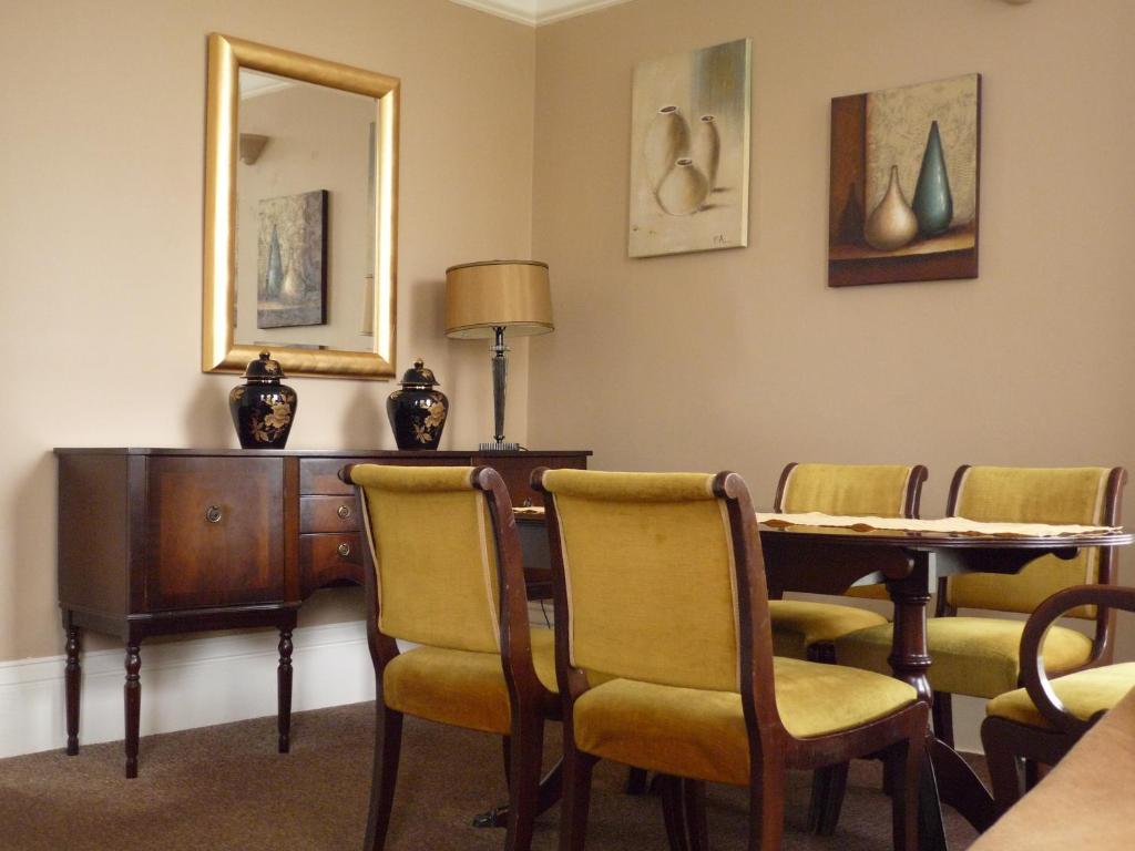 um quarto com uma mesa e cadeiras e um espelho em Paragon Serviced Apartments em Cheltenham