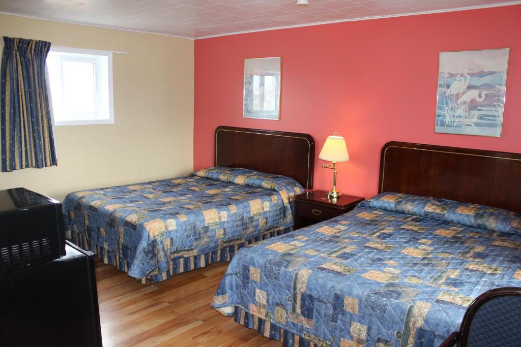 um quarto de hotel com duas camas e paredes vermelhas em Colonial Motel em Chatham