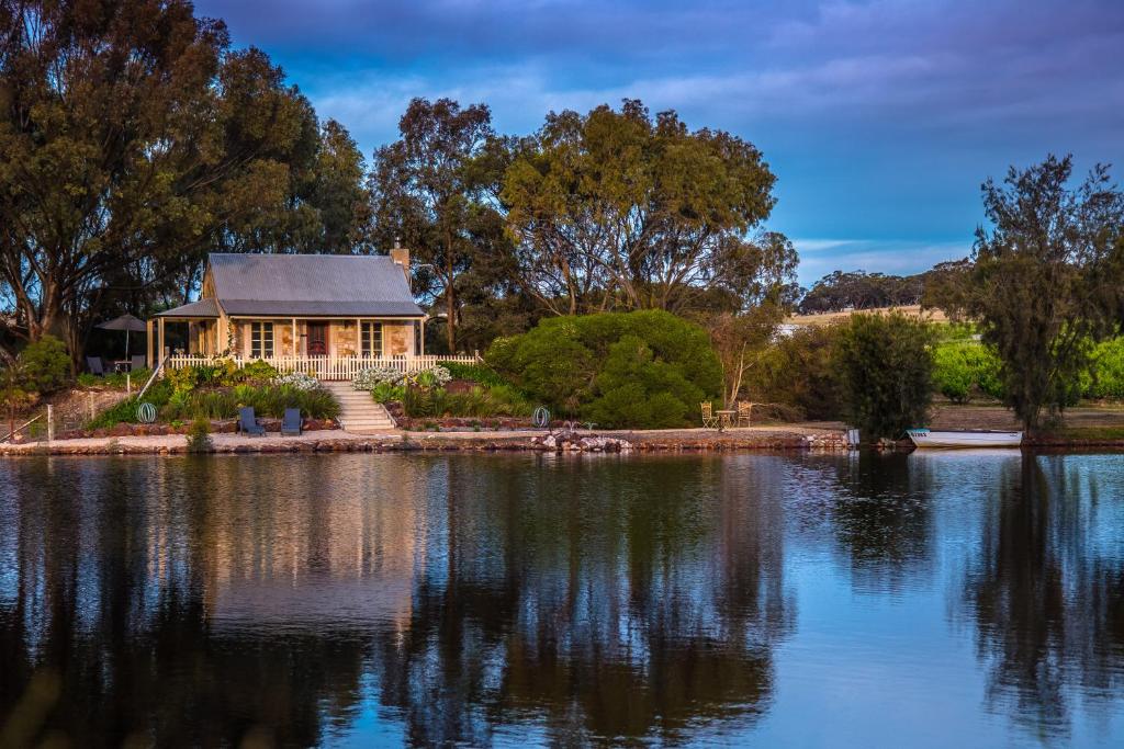 a house sitting on the shore of a lake at Stonewell Cottages and Vineyards in Tanunda