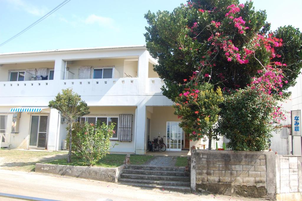 un edificio blanco con flores rosas delante en Minshuku Namisou, en Iriomote