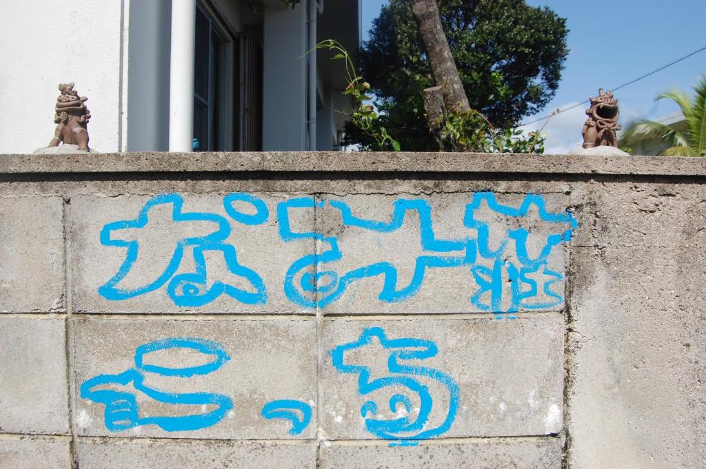 a cement wall with blue writing on it at Minshuku Namisou in Iriomote