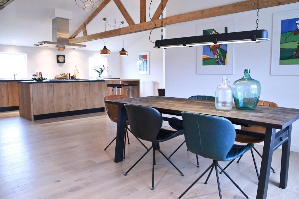 cocina y comedor con mesa de madera y sillas en Residentie De Hoek en Den Dungen