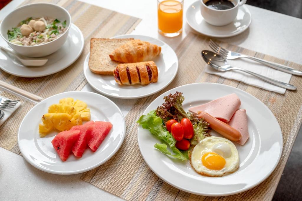 A plated breakfast spread combining hot dishes, fruit, pastries, and drinks.