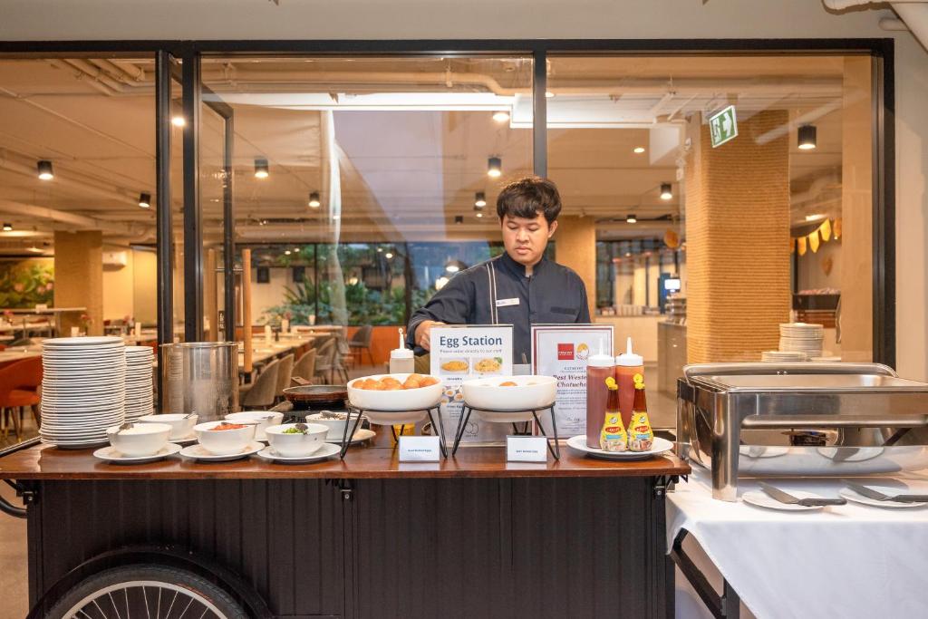 A staffed breakfast egg station with prepared dishes, condiments and buffet equipment.