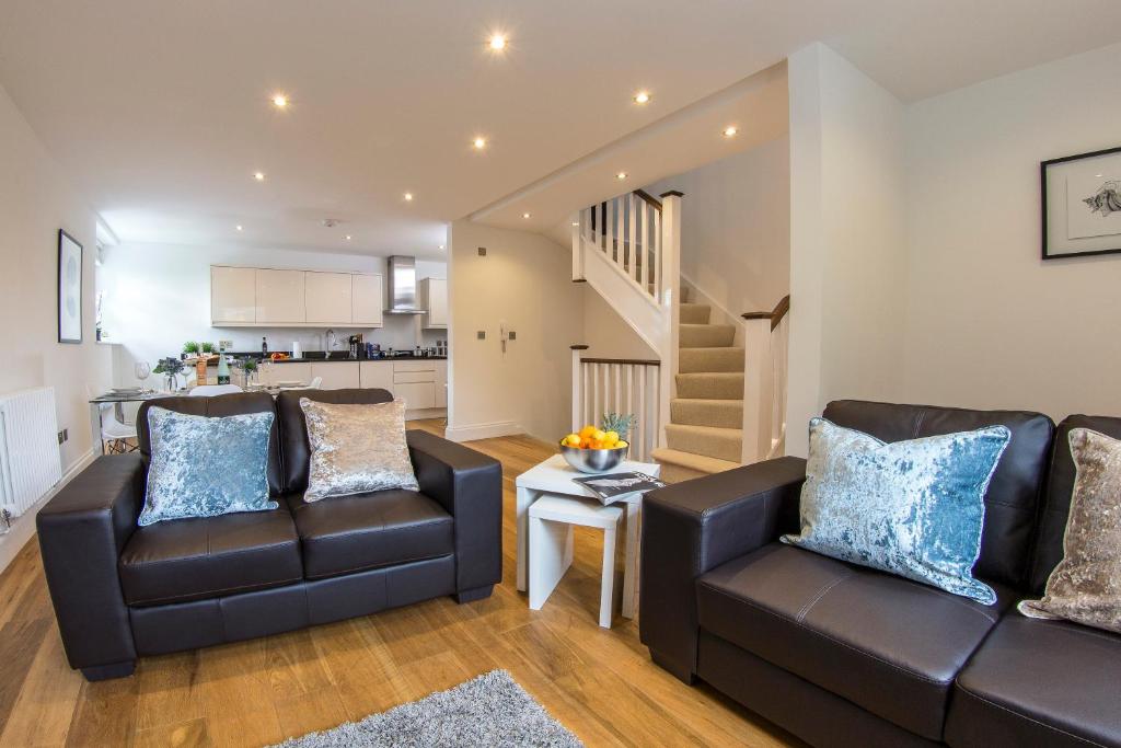 ein Wohnzimmer mit zwei Ledersesseln und einer Treppe in der Unterkunft Finchley Central Luxury 3 bed triplex loft style apartment in Hendon