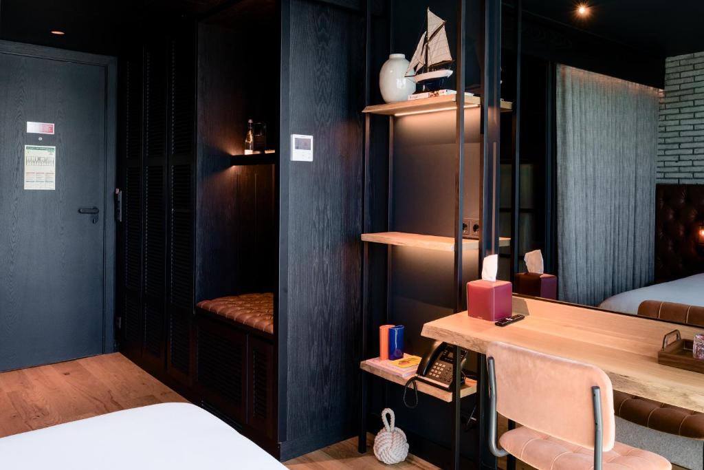A bedroom workspace sits beside open shelving and a mirrored wall.