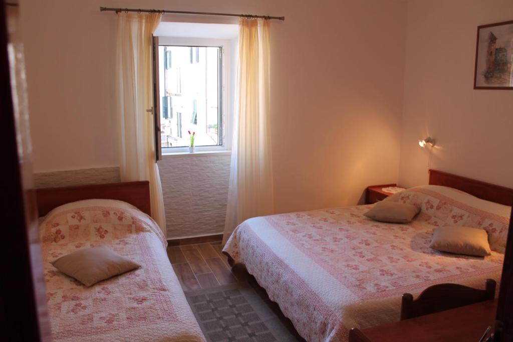 1 dormitorio con 2 camas y ventana en Apartments Nerio, en Dubrovnik