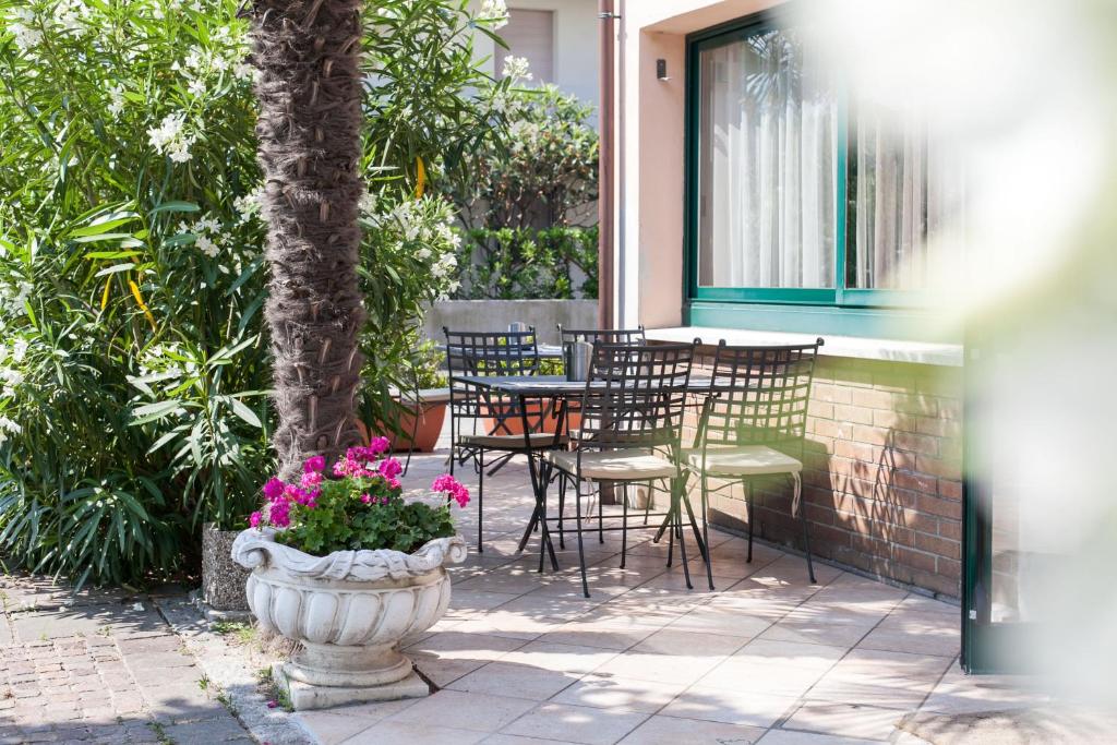 un patio con mesa, sillas y flores en Hotel Oasis, en Marina di Ravenna