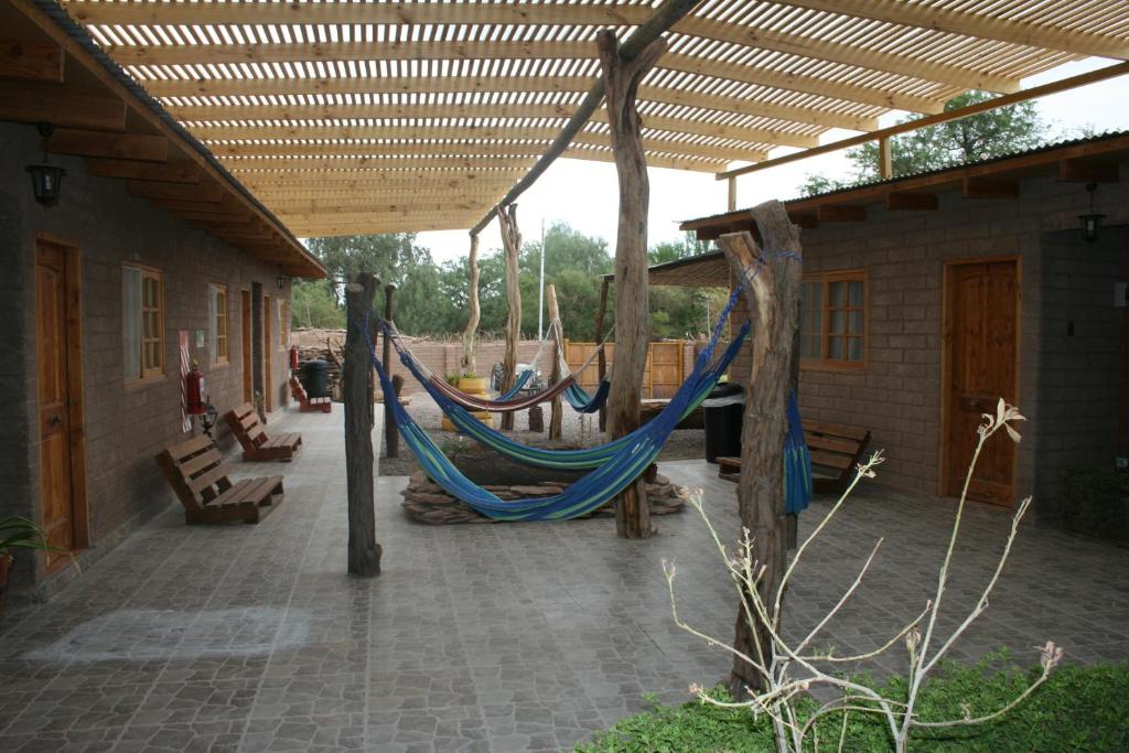 un patio con 2 hamacas bajo una pérgola en Hostal Km Zero El Huertillo, en San Pedro de Atacama