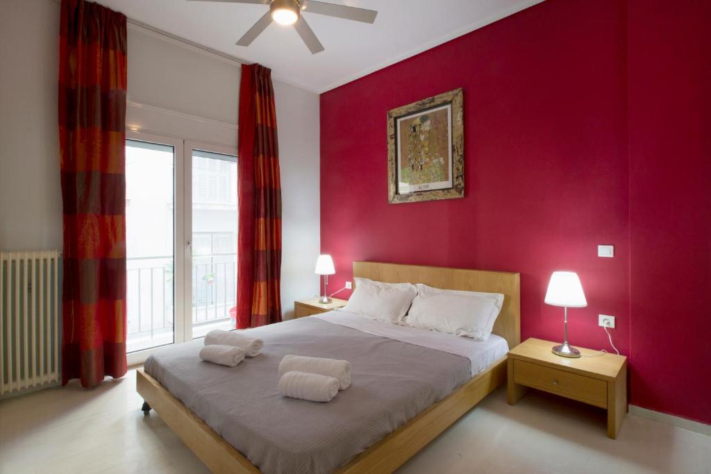 sypialnia z dużym łóżkiem z czerwoną ścianą w obiekcie Apartment at Acropolis Museum w Atenach
