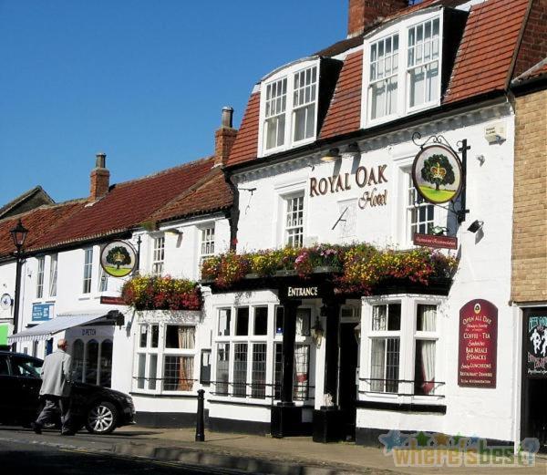 Ein Mann, der vor einem Gebäude die Straße hinuntergeht. in der Unterkunft Royal Oak Hotel in Great Ayton