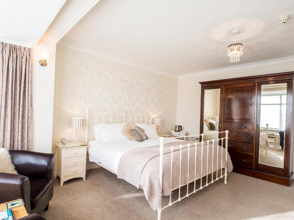 a bedroom with a white bed and a chair at The Coast Yard B & B and Garden Chalets in Selsey