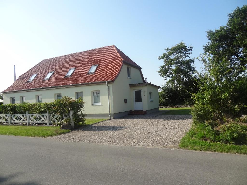 ein weißes Haus mit einem roten Dach und einer Auffahrt in der Unterkunft Land & Meer in Hasselberg