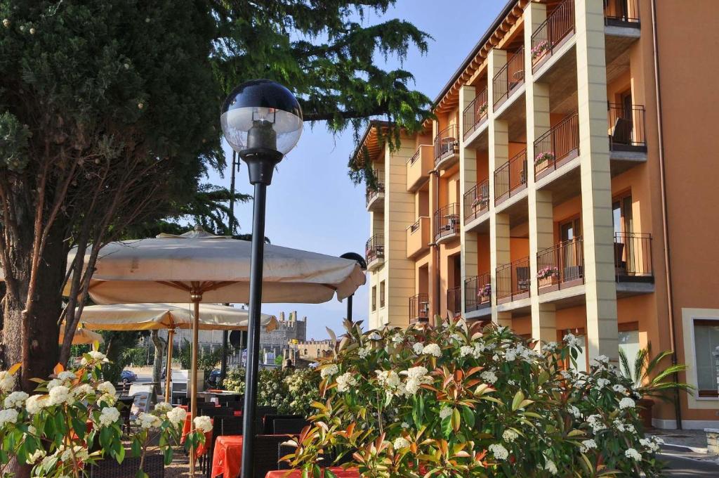 une lampe de rue avec des parasols devant un bâtiment dans l'établissement Hotel Lido, à Torri del Benaco