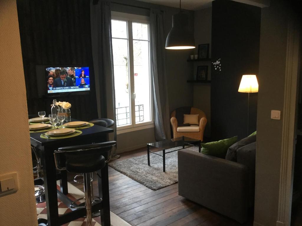 a living room with a couch and a table and a tv at Résidence Champs Bouillant in Soissons