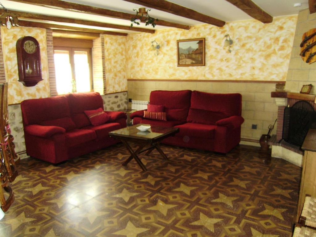ein Wohnzimmer mit zwei roten Sofas und einem Kamin in der Unterkunft Casa Rural La Coja in Villanueva del Condado