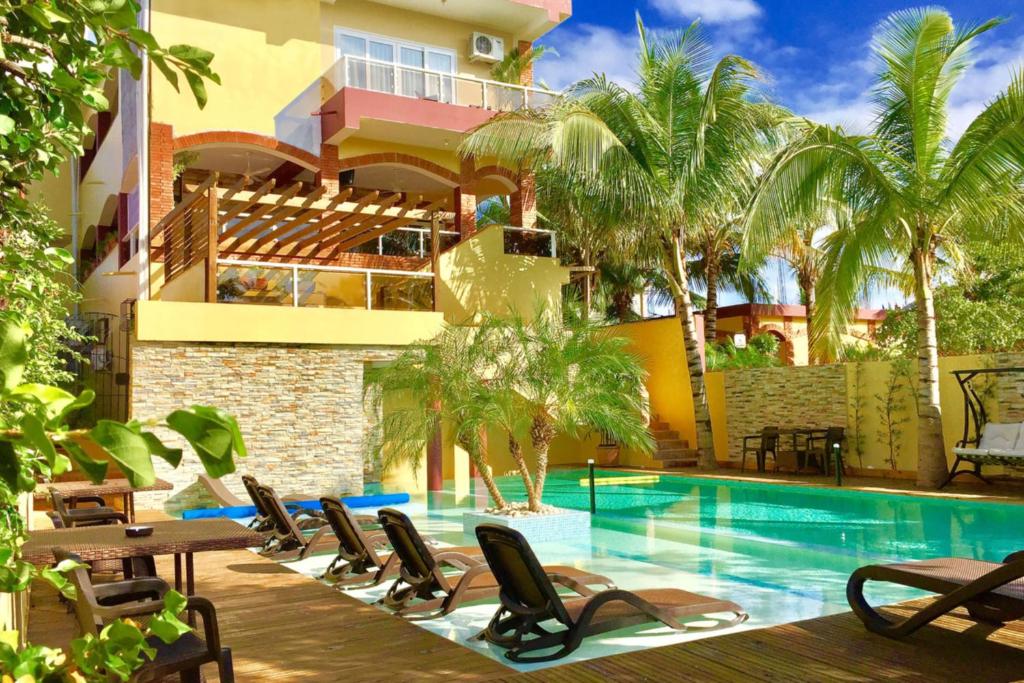 a resort with a swimming pool and chairs and a building at Sosua Inn Hotel in Sosúa