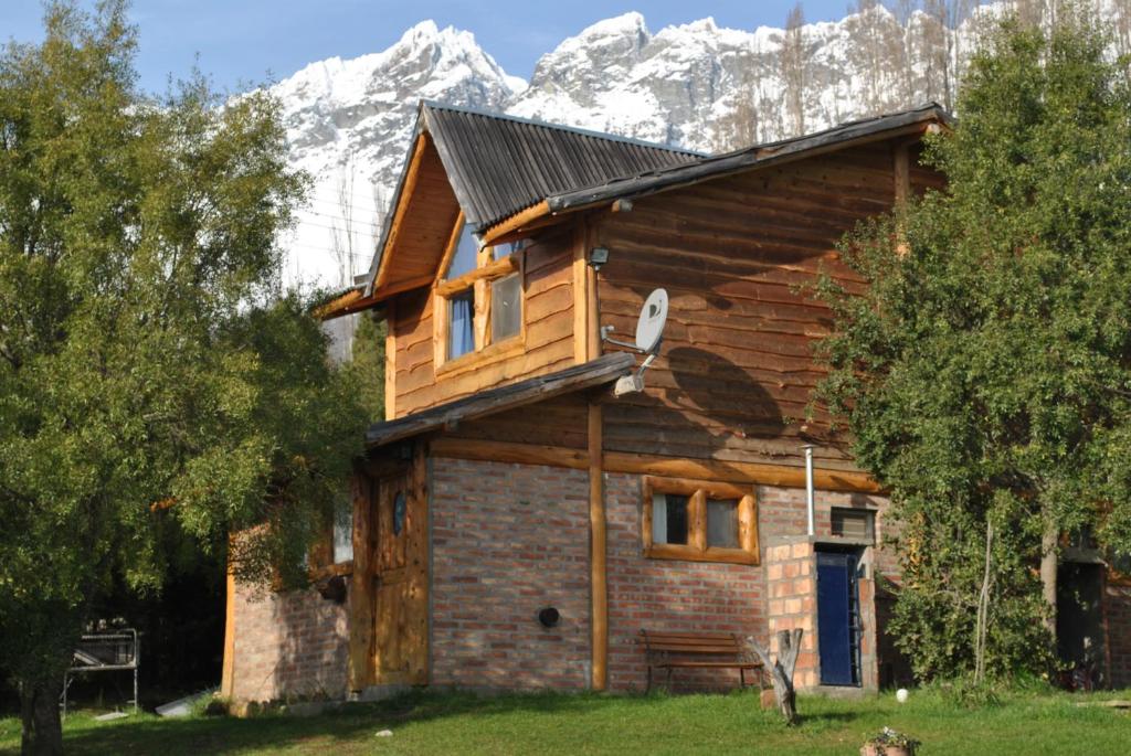 a log cabin with a snow covered mountain in the background at Cabañas Kairós in El Bolsón