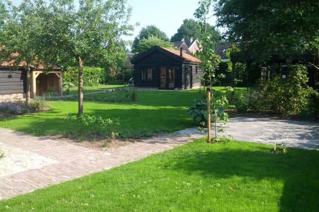 a yard with a house and green grass at Vakantiehuisje met bedstee in Diever