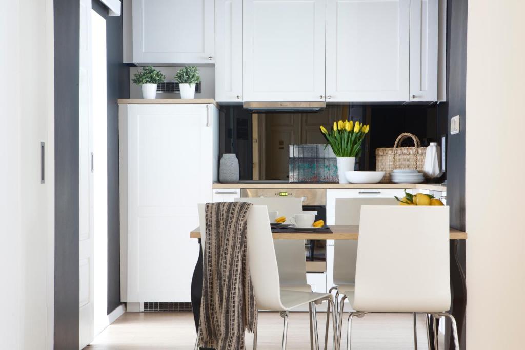 kuchnia z białymi szafkami, stołem i krzesłami w obiekcie Premium Class Apartments w Zagrzebiu