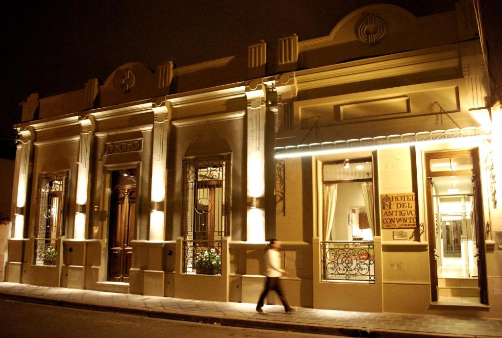 a person walking past a building at night at Hotel del Antiguo Convento in Salta