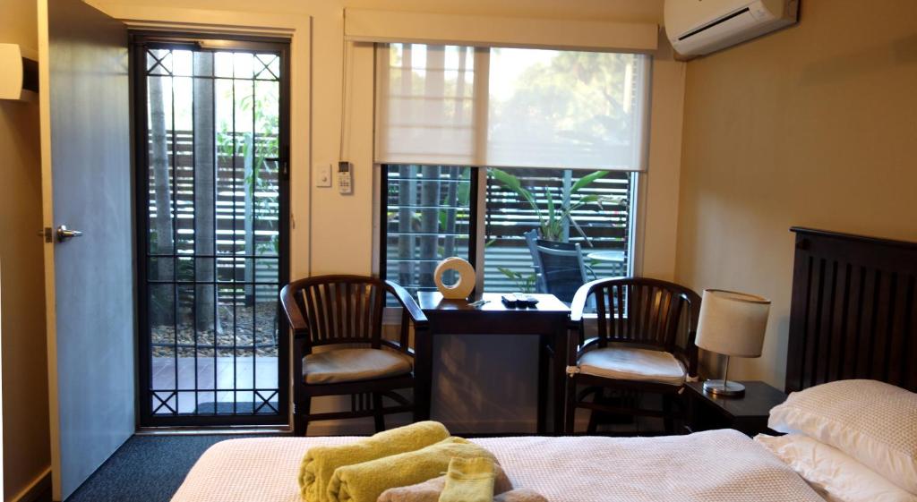 um quarto com uma cama, uma secretária e cadeiras em Bali Studio em Darwin