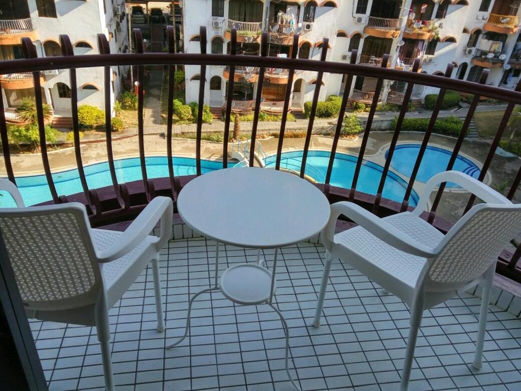 uma varanda com mesa e cadeiras e uma piscina em Pino's Place em Kuah