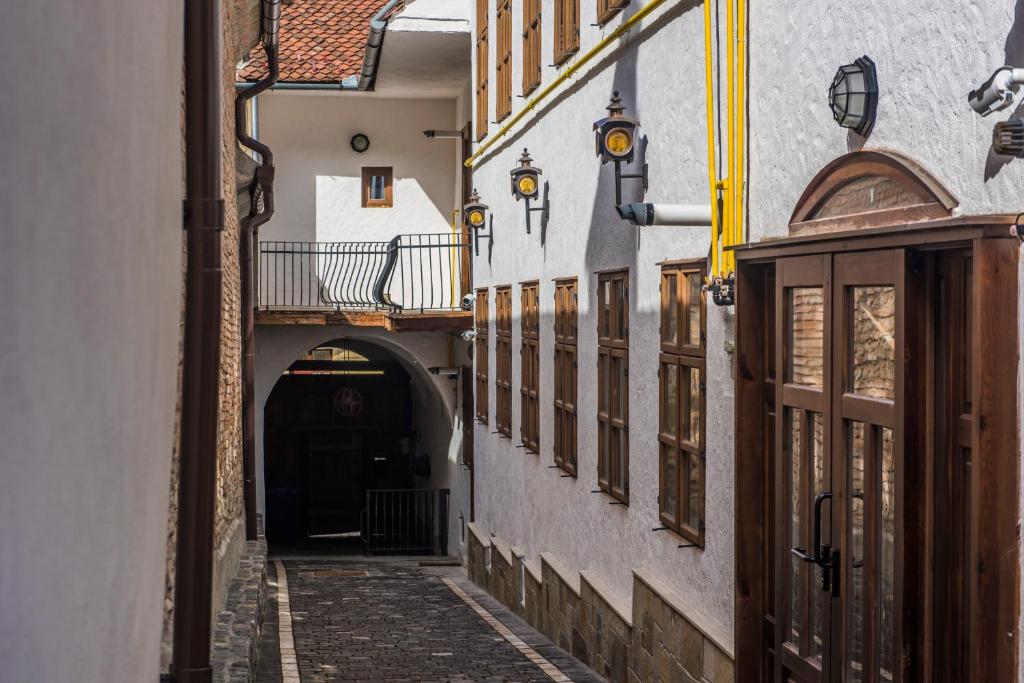 a narrow alleyway leads to a building with a clock on it at Casa Veche in Braşov