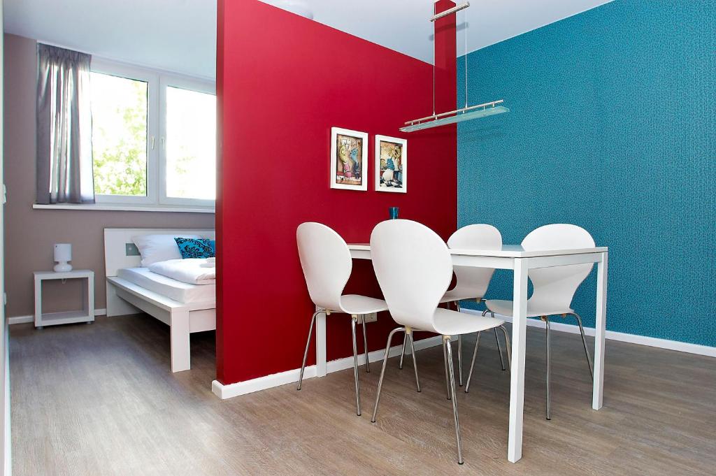 comedor con pared roja, mesa y sillas en Apartmenthouse Berlin - Am Görlitzer Park en Berlín