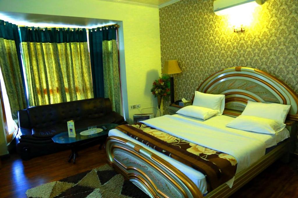 a bedroom with a large bed and a couch at Alaf Laila Guest House in Abbottabad