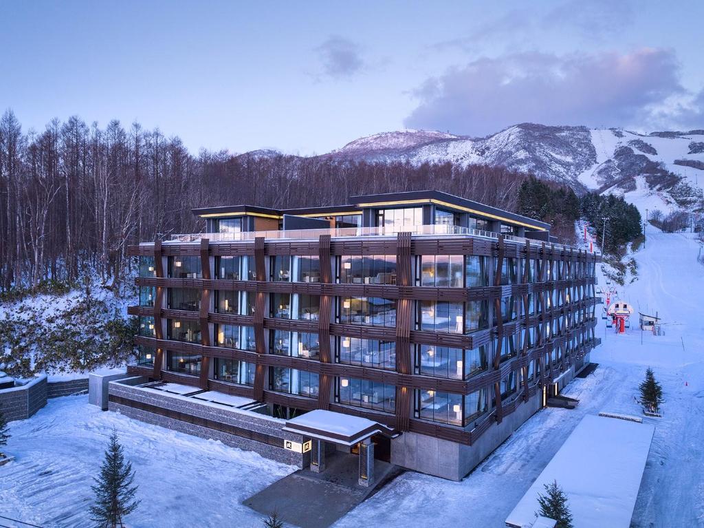 a building in the snow with mountains in the background at Aya Niseko in Niseko