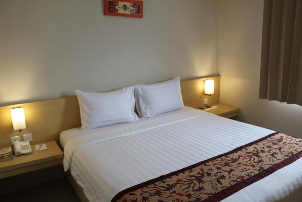 une chambre d'hôtel avec un grand lit et deux lampes dans l'établissement Bekizaar Hotel Surabaya, à Surabaya
