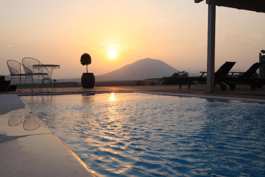 una puesta de sol sobre una piscina con una montaña en el fondo en Nof Einsof en Kefar Qish