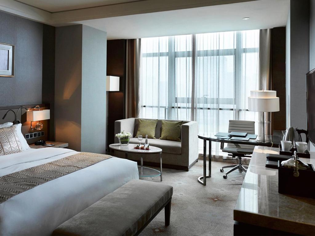a bedroom with a bed and a couch and a desk at Melia Jinan in Jinan