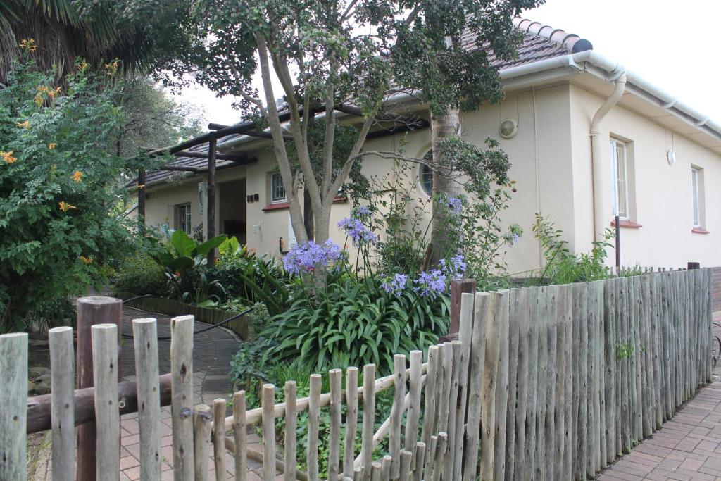 una valla de madera frente a una casa con flores en At Home BB en Estcourt