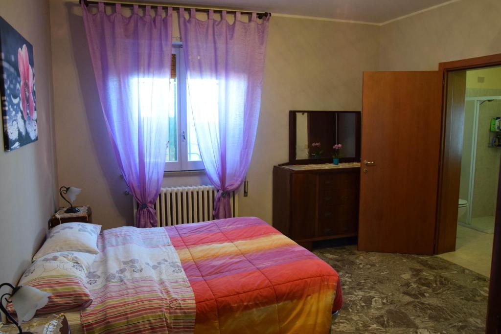 um quarto com cortinas roxas, uma cama e uma janela em La Scogliera B&B em San Vito Chietino