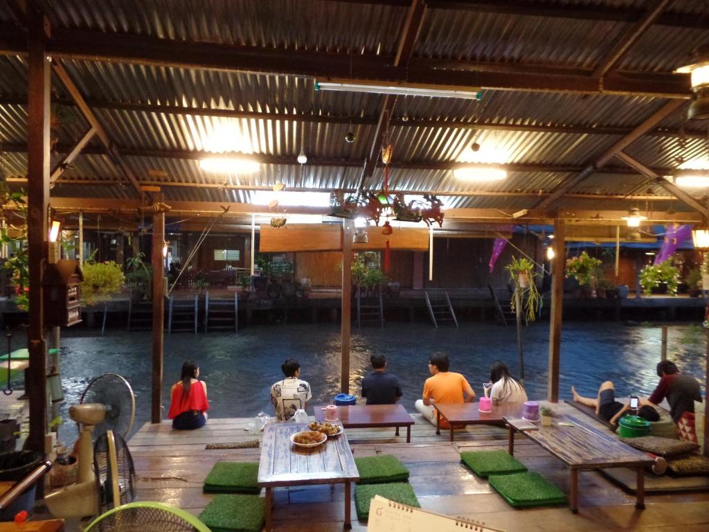 un grupo de personas sentadas alrededor de una mesa junto al agua en Ban Mae Arom, en Amphawa