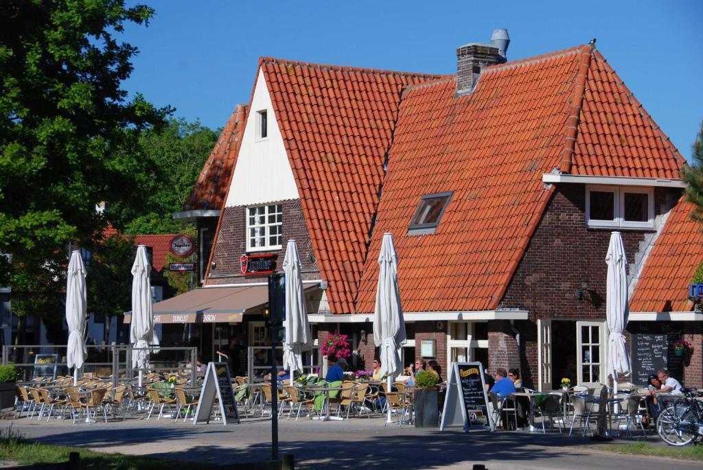 un groupe de parapluies et de tables devant un bâtiment dans l'établissement Duinlust Dishoek, à Dishoek