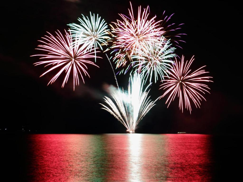 a group of fireworks exploding in the sky over the water at Toya Gokirakutei in Lake Toya