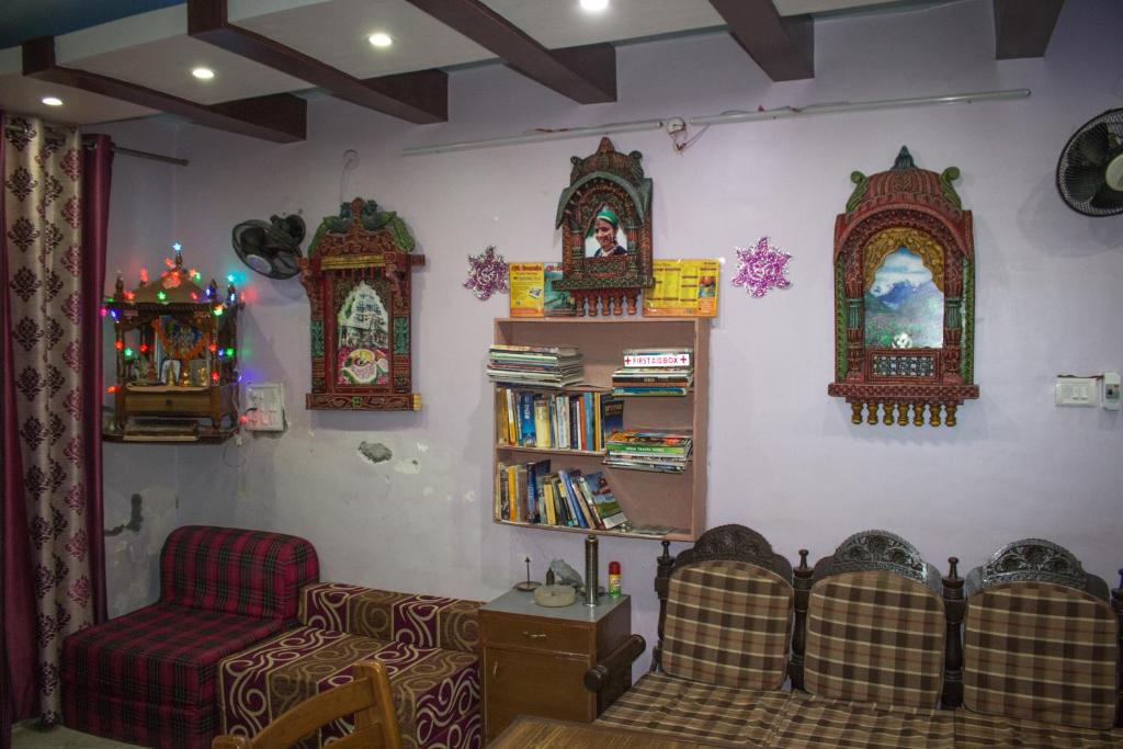 a living room with a couch a chair and a book shelf at Hotel Golden Crown Laxman Jhula in Rishīkesh