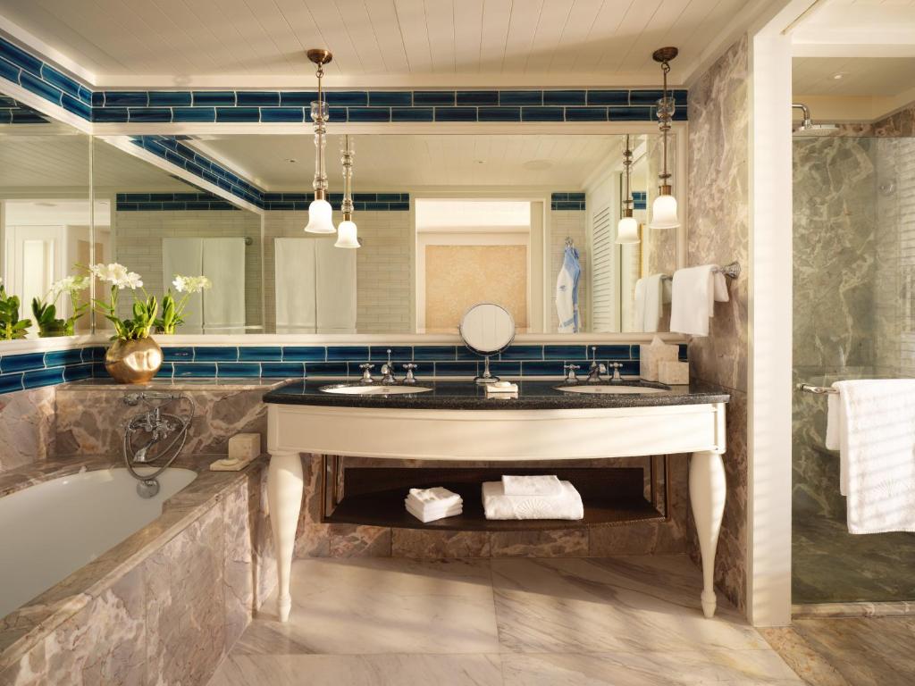 A marble bathroom centers on a freestanding-style vanity, tub, and full-width mirror.